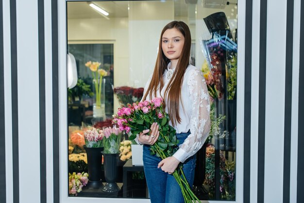 A young girl poses with a beautiful festive bouquet against the background of a cozy flower shop Floristry and bouquet making in a flower shop Small business