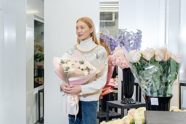 A young girl poses with a beautiful festive bouquet against the background of a cozy flower shop Floristry and bouquet making in a flower shop Small business