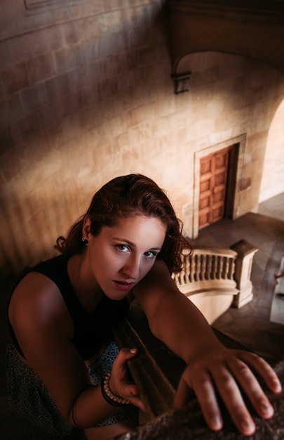 Young girl posing on the banister of a mansion