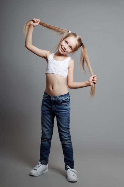 Photo young girl posing on a gray background, bright cheerful emotions on the girl's face