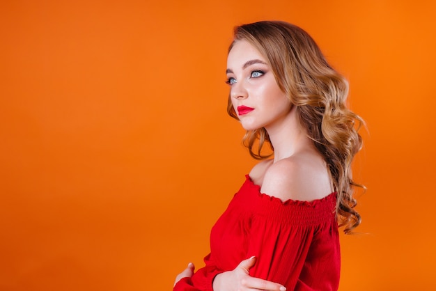 A young girl posing in studio with orange wall