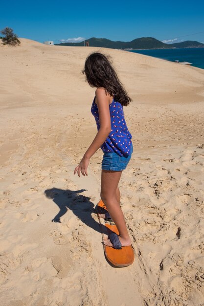 Young girl practicing sandbord in the dunes of Florianopolis, Brazil