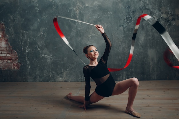 Giovane ragazza ginnasta professionista donna danza ginnastica ritmica con nastro in studio.