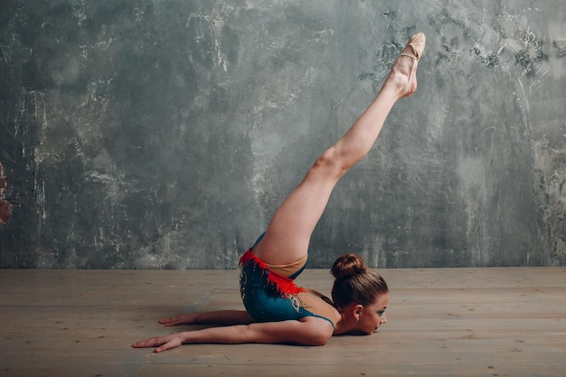 若い女の子のプロの体操選手の女性は、スタジオでリボンで新体操を踊ります。