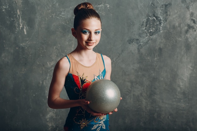 Молодая девушка профессиональный гимнаст женский портрет художественная гимнастика с мячом в студии.