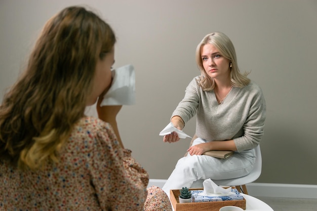 Young girl psychologist student pulls hand with paper handkerchief to client