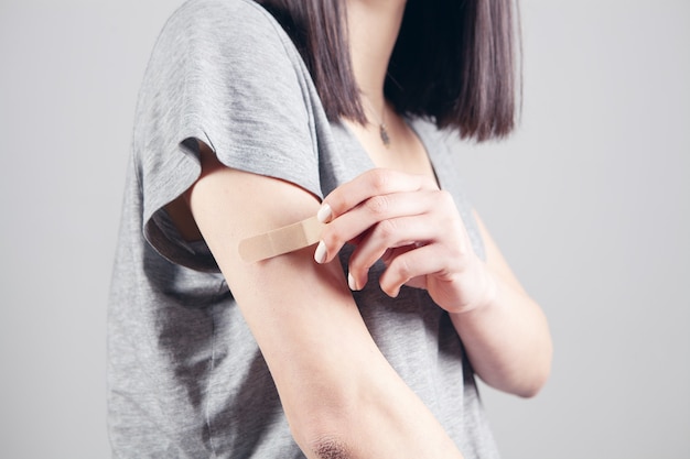 Young girl puts on a bandage on her arm