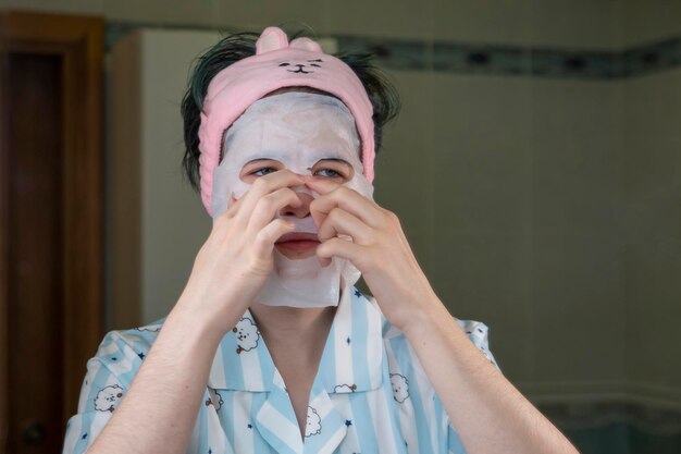 Photo a young girl puts a tissue cosmetic mask on her face. skin care, lifestyle.