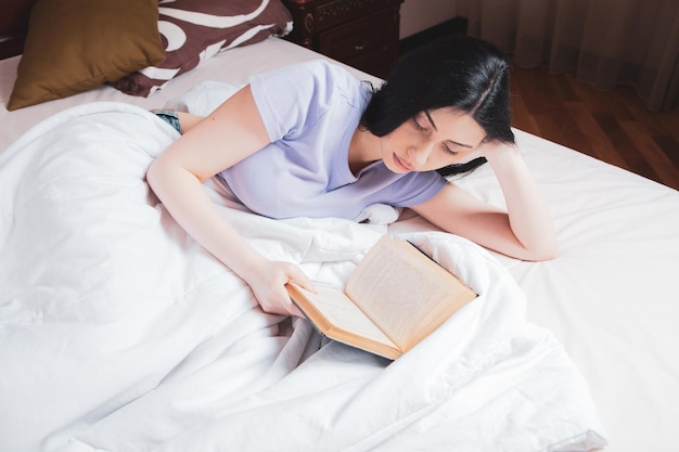 Young girl reading a book in bed