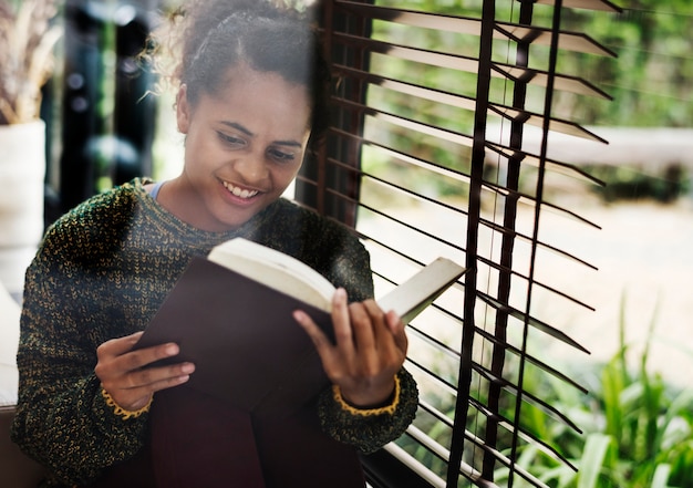 Young girl reading a book by the window