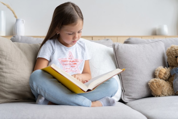 Young girl reading book at home. Distance education, home education. Self isolation concept.