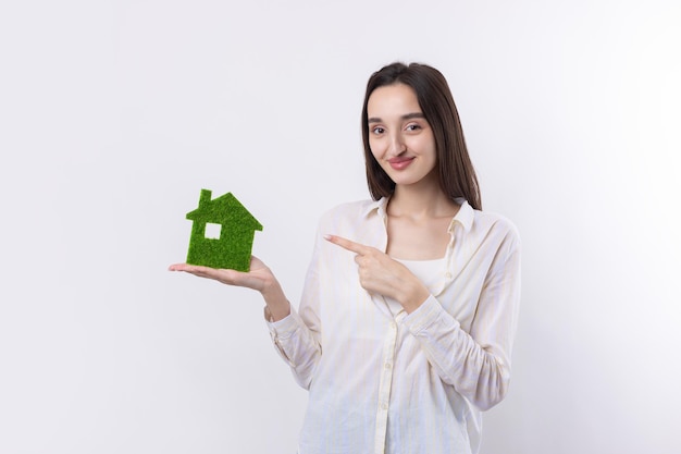 Una giovane ragazza agente immobiliare tiene in mano un modello di una casa verde vendita di immobili ecologici