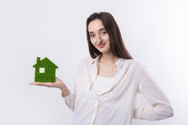 A young girl realtor holds a model of a green house in her hands Sale of ecological real estate