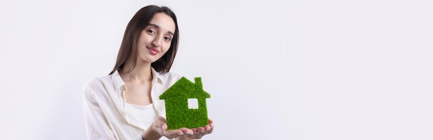 A young girl realtor holds a model of a green house in her hands Sale of ecological real estate