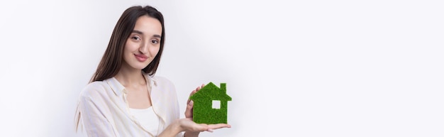 A young girl realtor holds a model of a green house in her hands Sale of ecological real estate