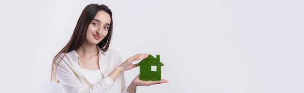 A young girl realtor holds a model of a green house in her hands Sale of ecological real estate