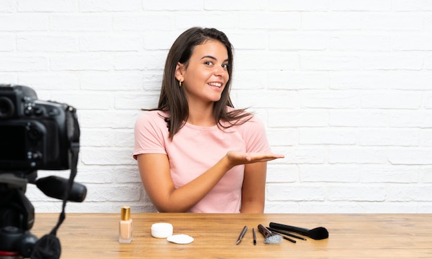 Young girl recording a video tutorial extending hands to the side for inviting to come