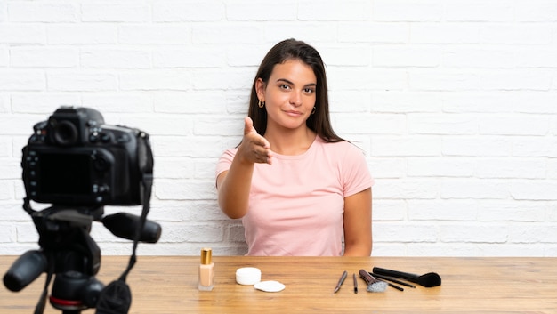 Young girl recording a video tutorial handshaking after good deal