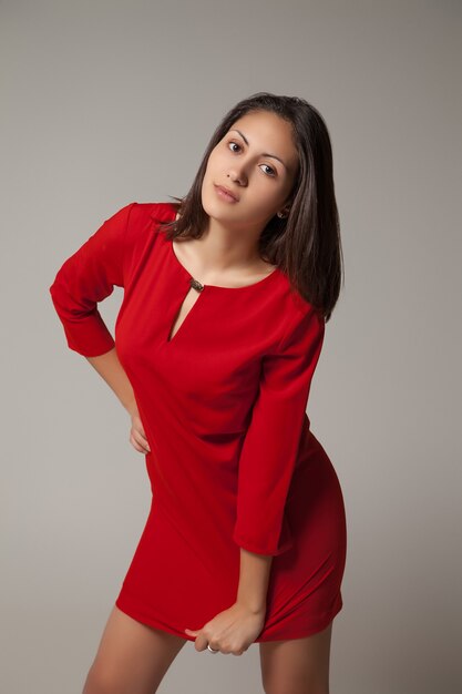 Young girl in red dress on gray background