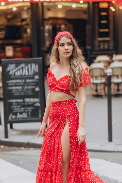 Young girl in red dress near Eiffel Tower in Paris on summer sunny day