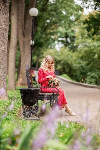 Young girl in a red dress sitting in the park