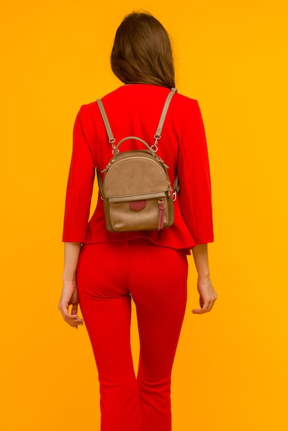 Young girl in a red suit with a small backpack on a yellow