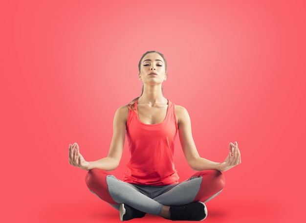 Young girl relaxing in yoga position on red