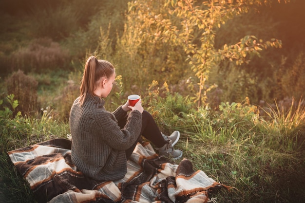 Young girl resting in the park on an autumn sunny day. Teenager lifestyle concept