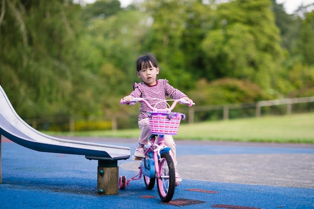 Young girl ridding bicycle in the summer garden morning