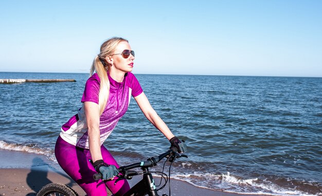 young girl rides a bicycle by the sea on a sunny day, cycling.