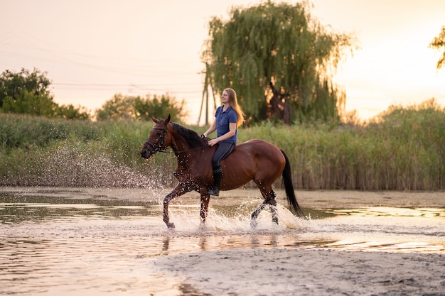 A young girl riding a horse on a shallow lake,