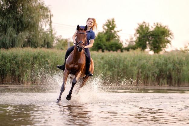 Young girl riding a horse on a shallow lake