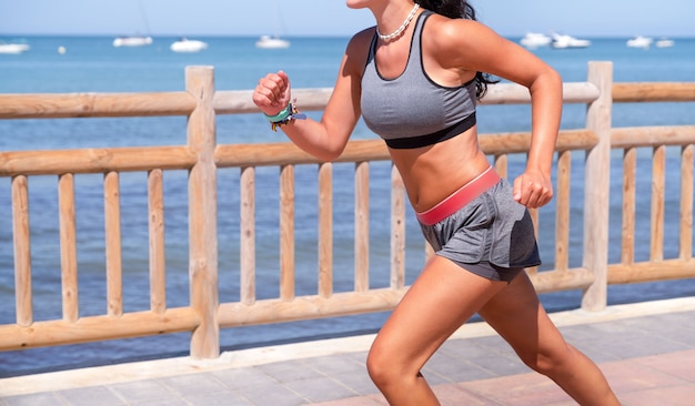 Young girl running on the beach with top and smartwatch and shorts and top on