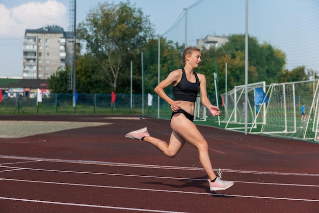 屋外のスタジアムでランニング トラックを走っている若い女の子