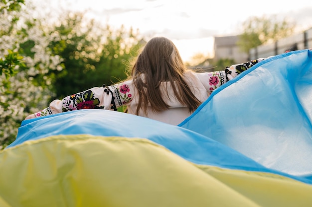 ウクライナの旗を掲げて走る少女ウクライナの旗をケープに掲げて走る少女の写真