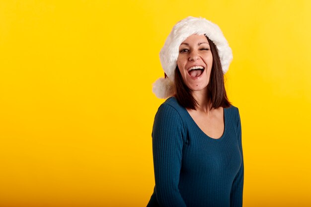 A young girl in a Santa Claus hat with a yellow background