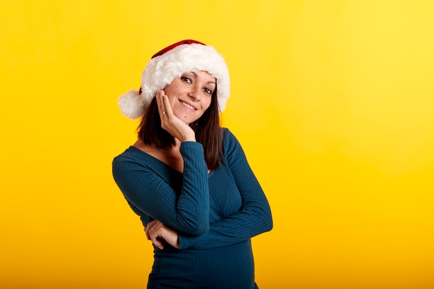 Молодая девушка в шапке Деда Мороза на желтом фоне