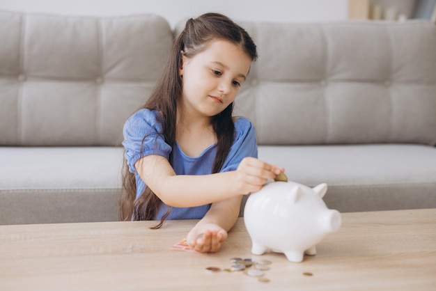 young girl saving money with piggy bank at home
