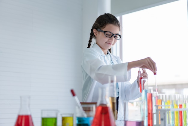 실험실 방에서 유리 튜브에 화학 실험을 만드는 어린 소녀 과학자