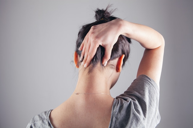 Photo young girl showing neck on gray