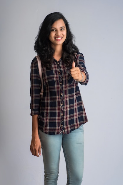 Young girl showing thumb with the backpack