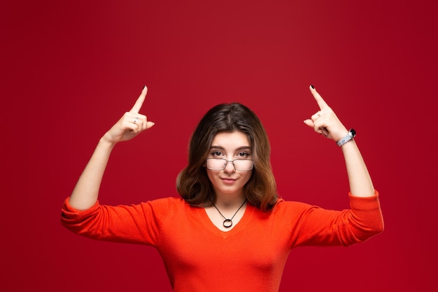 Young girl shows thumbs up on the of a red wall