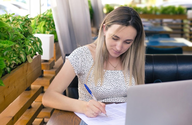 A young girl signs documents sitting in a cafe