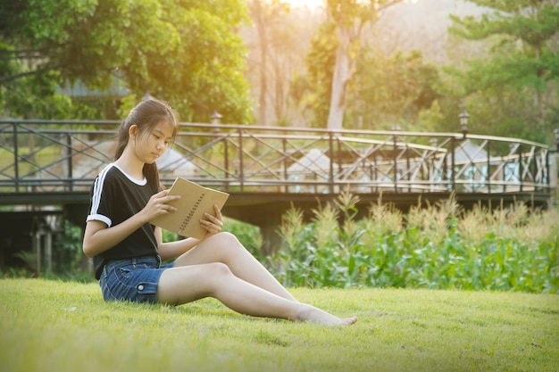 Young girl sit on grass and reading book