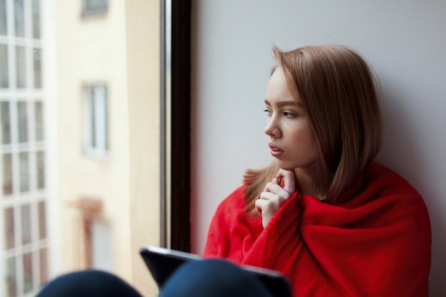 A young girl sits by the window.