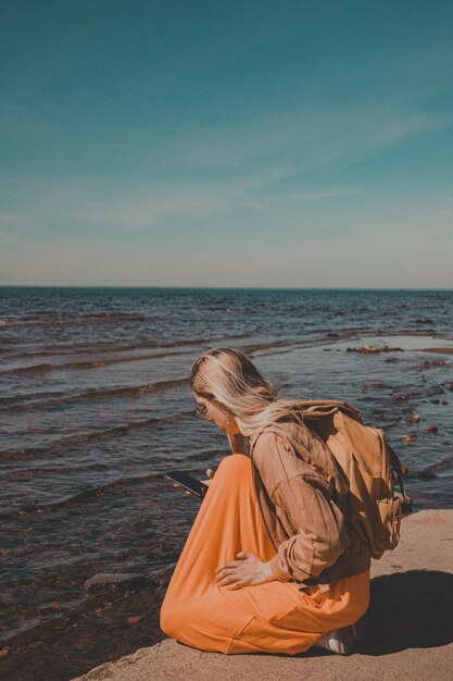 Young girl sits near the sea water on a beach