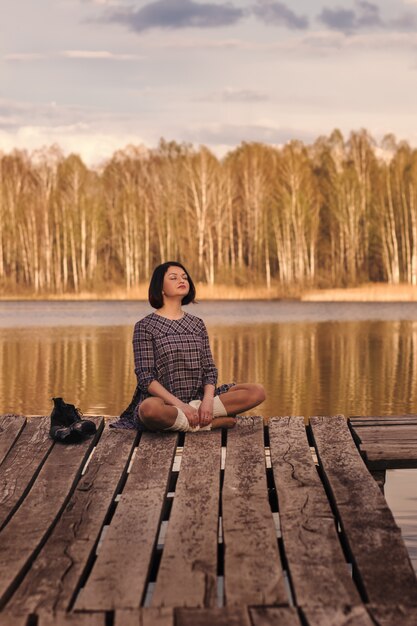 Photo young girl sits on a pier in a summer dress