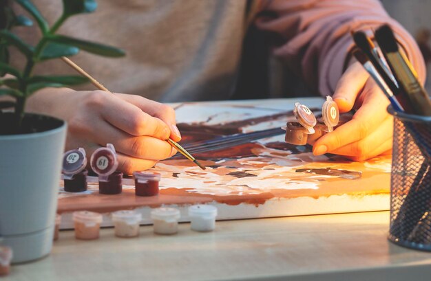 A young girl sits at a table and paints A favorite hobby an activity for the soul