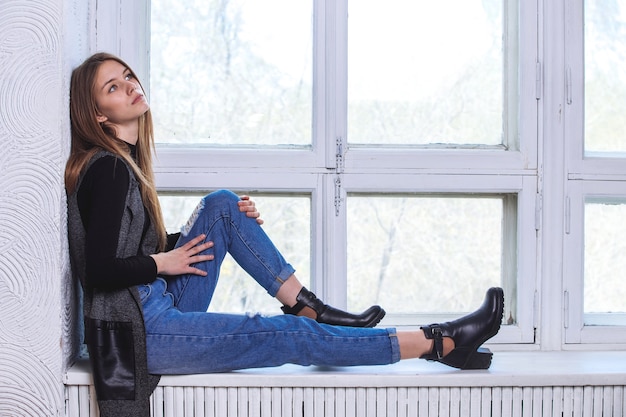 A young girl sits on the windowsill. In the Studio.