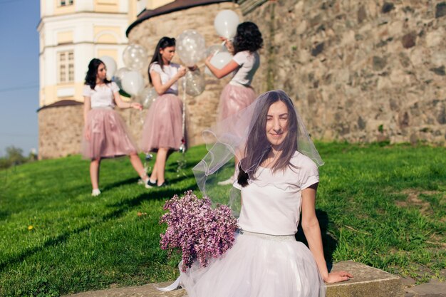 La ragazza si siede con un bellissimo bouquet e il suo viso è coperto di velo